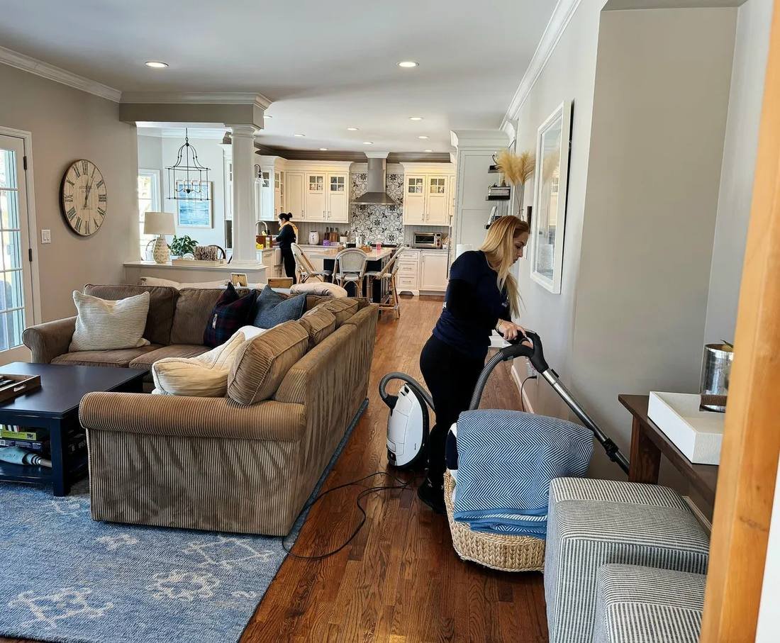 Cynthia's cleaner vacuuming a bright open-plan living room in a Westchester home