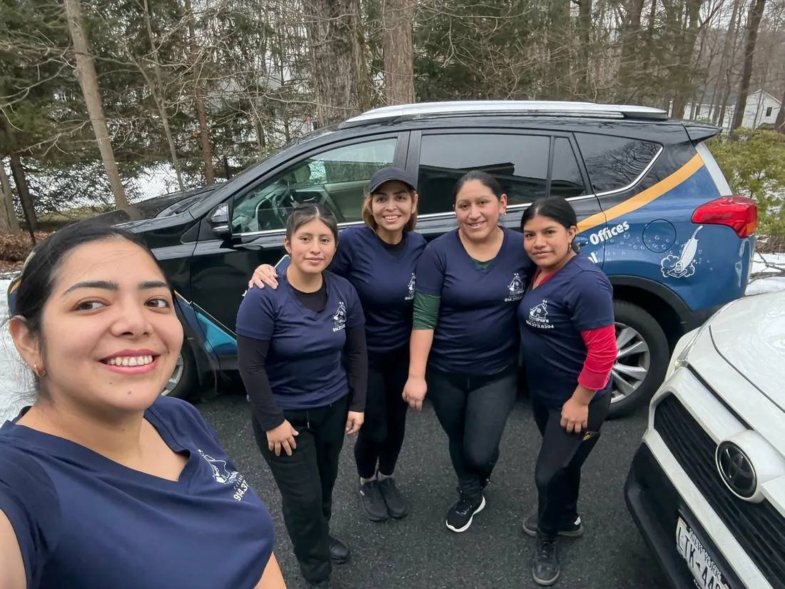 The Cynthia's Cleaning Services team in navy uniforms beside the branded company vehicle